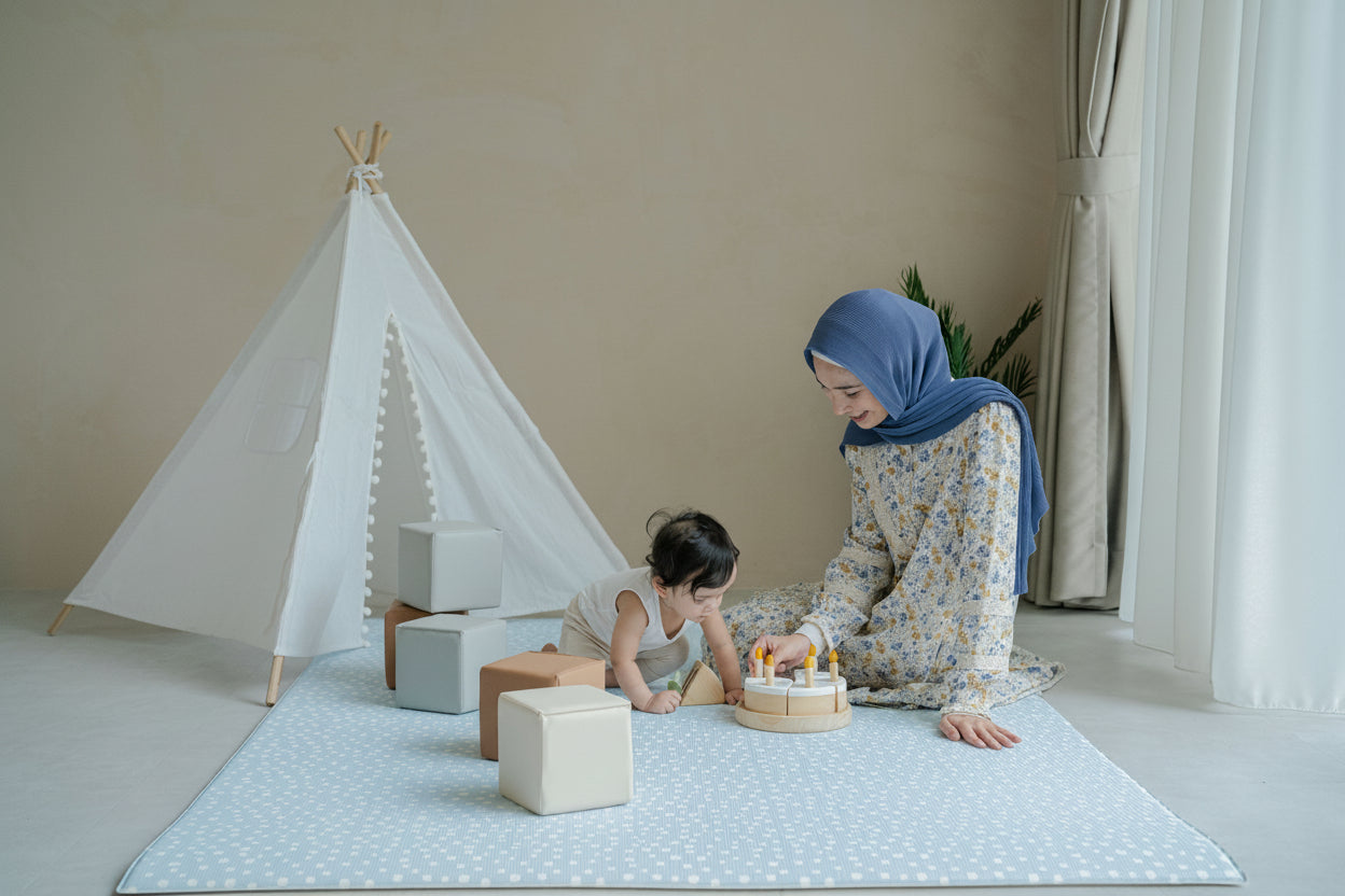 Woman and child playing with a small tent and blocks on a light-colored floor.